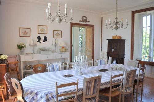 uma sala de jantar com uma mesa branca e cadeiras em Vaste maison 23/29 pers. piscine proche des plages em Longeville-sur-Mer