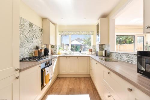 a kitchen with white cabinets and a large window at The Waves by inspirestays-com in Rustington