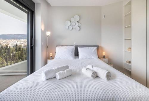 biała sypialnia z dużym łóżkiem i ręcznikami w obiekcie Upscale Luxury Living in Acropolis by Neuvel w Atenach