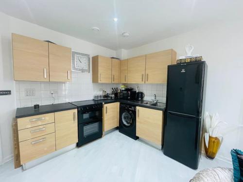 eine Küche mit einem schwarzen Kühlschrank und Holzschränken in der Unterkunft Spacious one bedroom ft in Central London King’s Cross in London