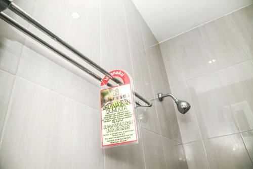 a sign in a shower in a bathroom at Istanaku Guesthouse 2 in Manado