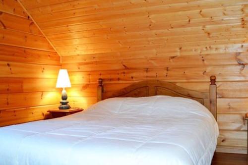 um quarto com uma cama branca numa parede de madeira em Grand chalet en bois avec vue splendide em Le Dévoluy