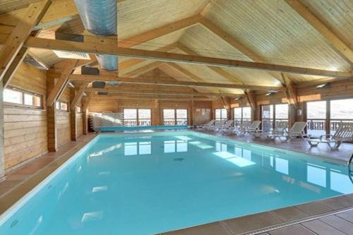 uma grande piscina interior com tecto de madeira em Grand chalet en bois avec vue splendide em Le Dévoluy