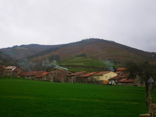 a village with a green field and a mountain at Posada Rural Peñasagra in Quintanilla