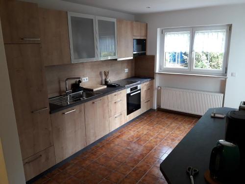 a kitchen with wooden cabinets and a tile floor at Ferienwohnung Brehmbachgrund in Tauberbischofsheim