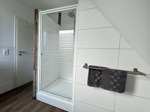 a bathroom with a glass shower with a towel rack at Pension Blaue Nordseewelle in Neuharlingersiel