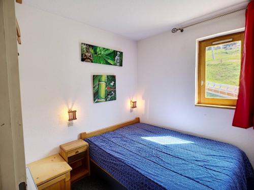 une chambre avec un lit bleu et une fenêtre dans l'établissement Les Menuires 3 pièces, 6 pers, pieds des pistes, animaux admis - FR-1-178-32, aux Menuires
