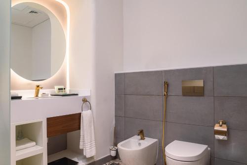 y baño con aseo, lavabo y espejo. en Mina Hotel and Residences By The Torch en Doha