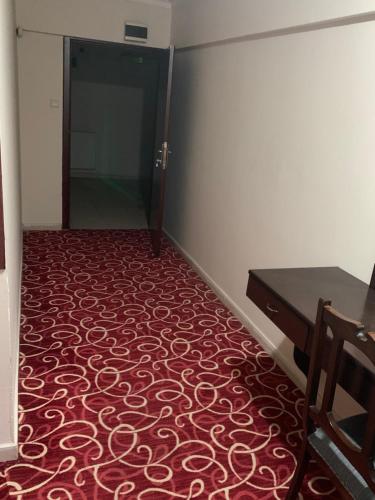 Habitación con suelo de moqueta roja y escritorio. en Ankara apart Hostel 2 en Altındağ