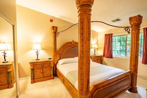 a bedroom with a wooden canopy bed and two night stands at Grand Wood Suites in Nashville