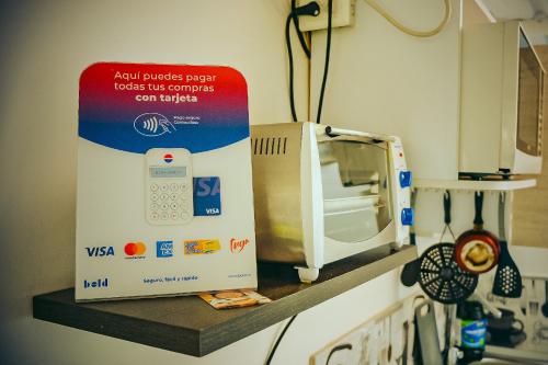 un four micro-ondes installé sur une étagère dans une cuisine dans l'établissement Hostel Metro Floresta Alojamiento, à Medellín
