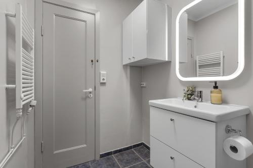 Baño blanco con lavabo y espejo en Sunny Reykjavík Apartment, en Reikiavik