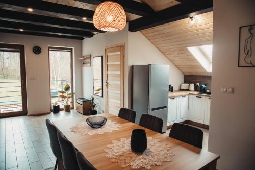 a kitchen and dining room with a table and a refrigerator at Tree&Water Apartament nad jeziorem Ublik in Ublik