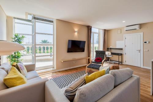a living room with a couch and a tv at Setubal Prime Penthouse in Setúbal
