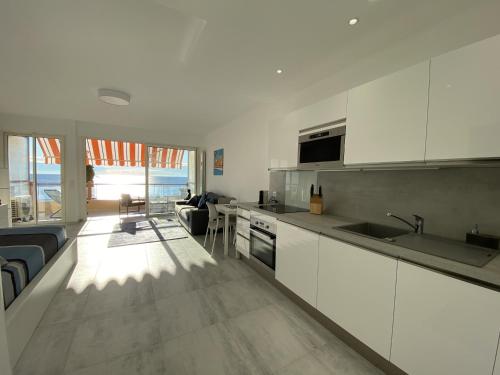 a kitchen with white cabinets and a living room at Le Vigia in Menton