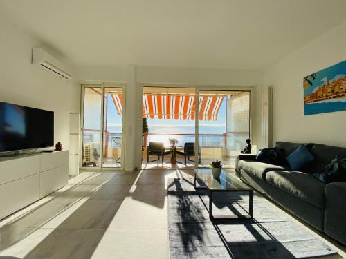 un salon avec un canapé et une télévision dans l'établissement Le Vigia-vue mer-terrasse-climatisation-parking, à Menton