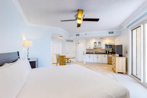 a bedroom with a white bed and a kitchen at Sterling Sands 614 in Destin