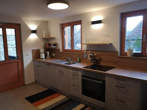 cocina con fregadero, fogones y ventanas en Ferienwohnung im Auszeithaus Hohenlohe, en Forchtenberg