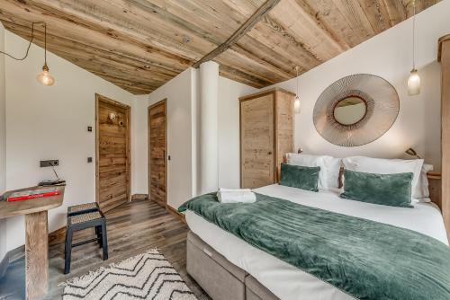 a bedroom with a large bed and a wooden ceiling at Hotel & Spa Le Val d'Isère in Val dʼIsère