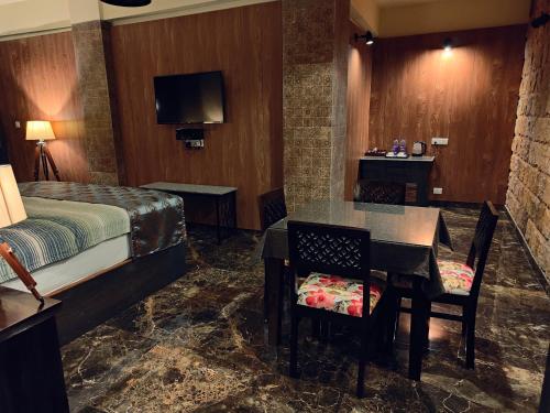 una camera d'albergo con letto, tavolo e sedie di Hotel Acropolis a Shillong