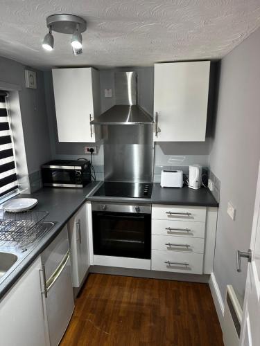 a kitchen with white cabinets and a stove top oven at VM Holiday let in Great Yarmouth