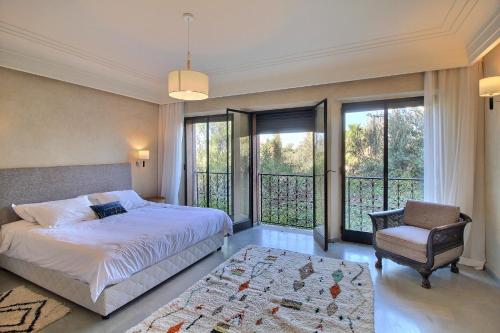 sypialnia z łóżkiem, krzesłem i oknami w obiekcie Villa Touareg Domaine des Kasbahs w Marakeszu