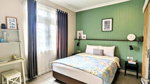 1 dormitorio con cama y pared verde en Cottonwood Bed & Breakfast House Bandung en Bandung