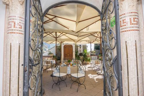 an open gate to a patio with tables and chairs at Villa Palumbo in Positano