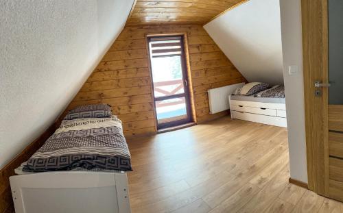 a attic bedroom with a bed and a window at Chata Holder in Svätý Kríž