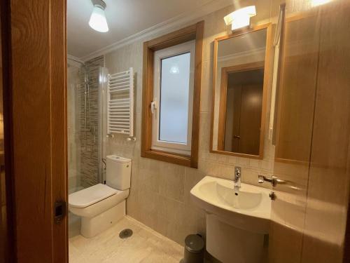 bagno con servizi igienici, lavandino e specchio di Housingcoruña ORILLAMAR a La Coruña