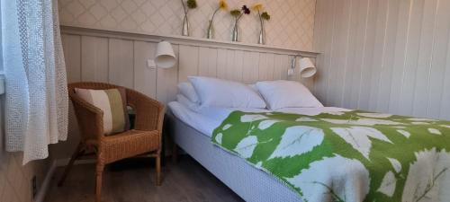 a bed with a green and white comforter and a chair at Erzscheidergaarden Hotell in Røros