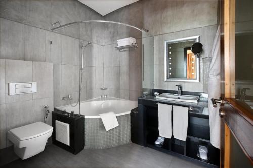 a bathroom with a tub and a toilet and a sink at Park Suites Hotel & Spa in Casablanca