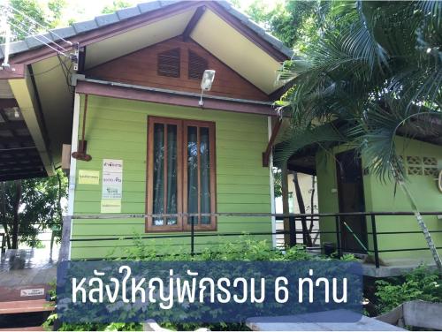 Parida Resort في سنغ بوري: منزل أخضر صغير مع وجود علامة أمامه