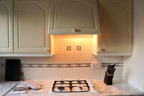 uma cozinha com armários brancos e uma placa de fogão em Lovely staycation with family FREE Parking & WiFi em Beeston