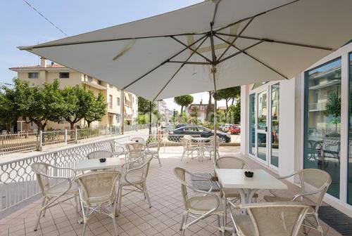 d'une terrasse avec des tables, des chaises et un parasol. dans l'établissement HOTEL CONTI, à San Mauro a Mare