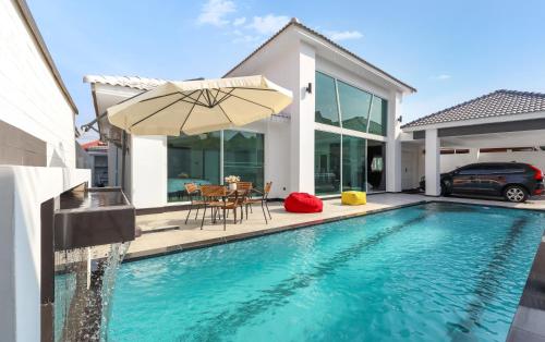 a swimming pool with an umbrella and a house at *City~house* 芭堤雅豪华泳池别墅近步行街 in Pattaya South