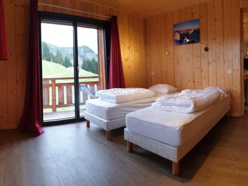 two beds in a room with a large window at Appartement Samoëns, 6 pièces, 14 personnes - FR-1-624-3 in Samoëns