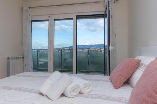 a bedroom with a bed with towels on it at Buarcos Sunset Apartment by Rent4All in Figueira da Foz