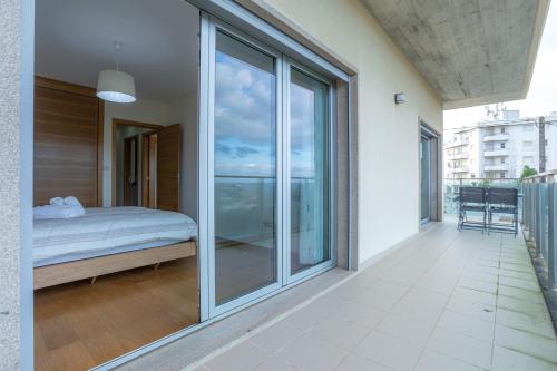 1 dormitorio con puertas de cristal y 1 cama en el balcón en Buarcos Sunset Apartment by Rent4All en Figueira da Foz