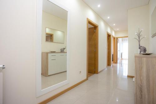 cocina con paredes blancas y espejo grande en Buarcos Sunset Apartment by Rent4All en Figueira da Foz