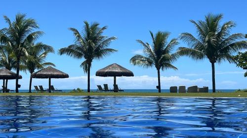 una piscina con palme e l'oceano di Guarajuba Paraíso a Camaçari