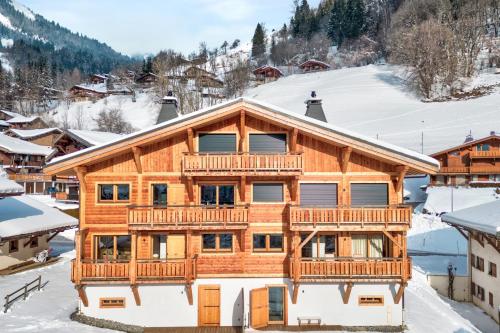 une maison en rondins avec une terrasse dans la neige dans l'établissement Duplex Aravis - Welkeys, à Praz-sur-Arly