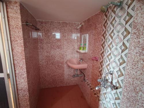 a pink bathroom with a sink and a shower at Camrose Guest House in Candolim