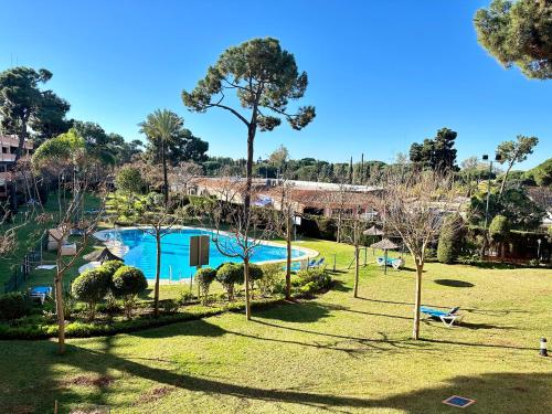 マルベーリャにあるApartamento en Marbellaのスイミングプールと木々のある公園の景色を望めます。