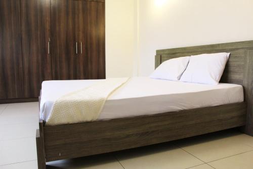 a bedroom with a wooden bed with white sheets and pillows at Matola View Residence in Matola