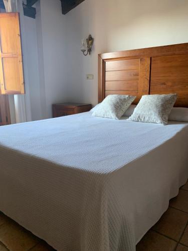 a bedroom with a large white bed with a wooden headboard at Hotel La Villa in Requena