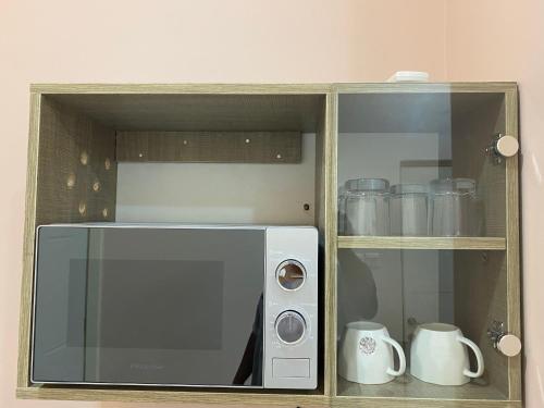 a microwave in a wooden cabinet with mugs at C7 Hazelwood Residence & Suites in Abuja