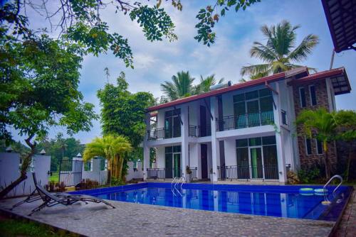 a large house with a swimming pool in front of it at Hotel Sanri Villa Katunayake in Minuwangoda