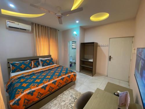 C7 Hazelwood Residence & Suites في أبوجا: غرفة نوم فيها سرير وتلفزيون