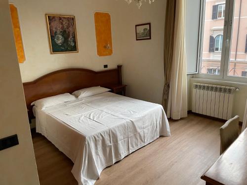 een slaapkamer met een bed met witte lakens en een raam bij Le Petit Real in Rome